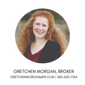 Picture of lady with long, red, curly hair wearing a black cardigan over a maroon top, smiling for the camera.