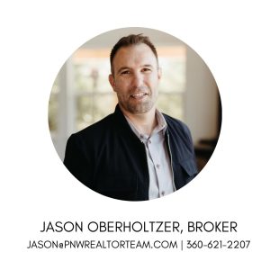 Gentleman wearing a gray button up under a black jacket, smiling for the camera.